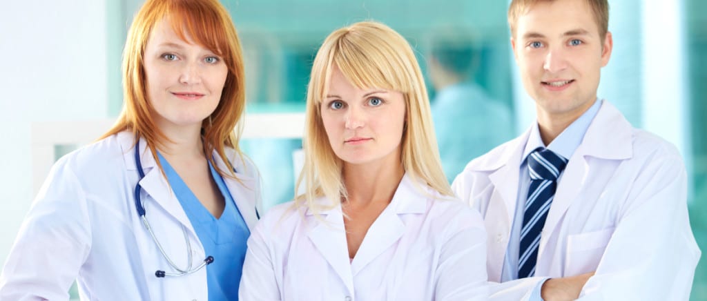 Portrait of three clinicians in white coats looking at camera